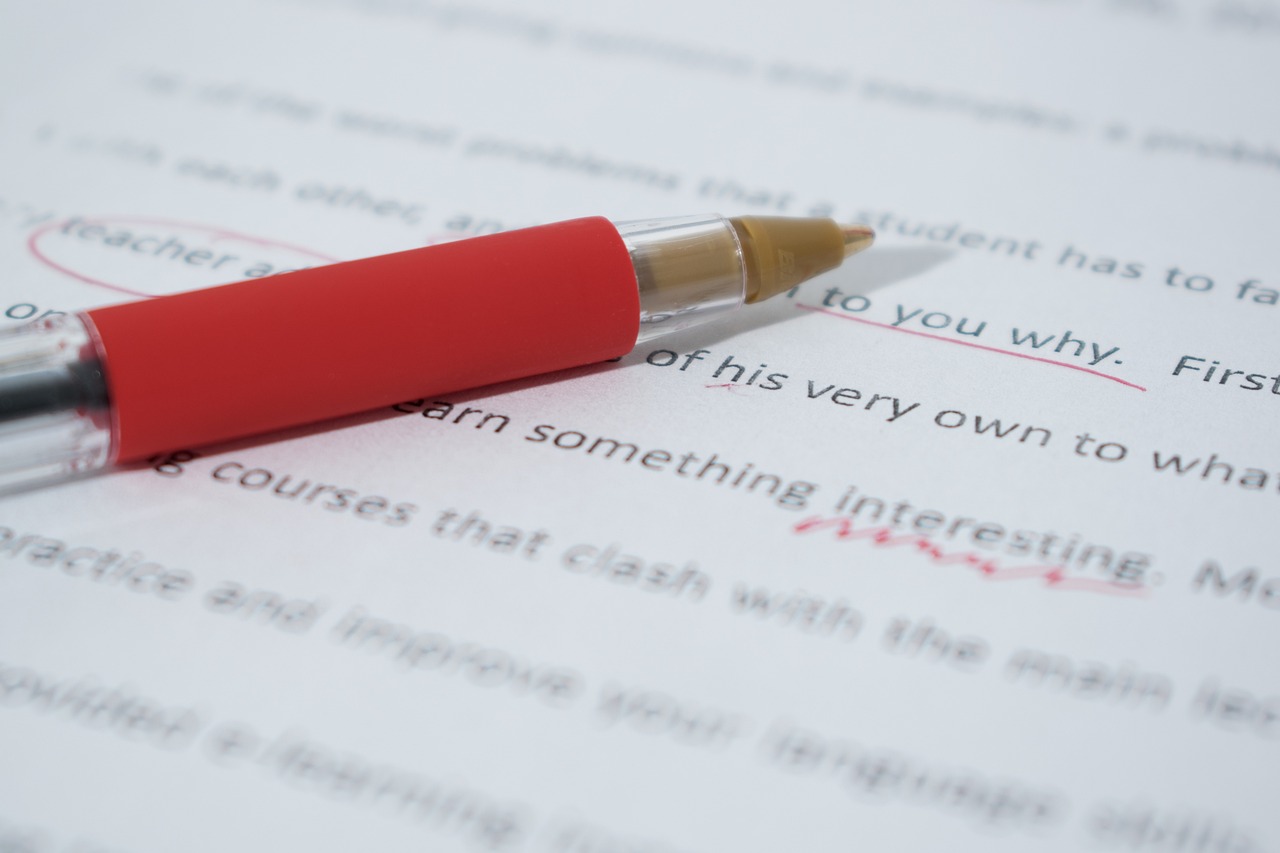 a red pen is on a typed piece of paper with corrections in red ink